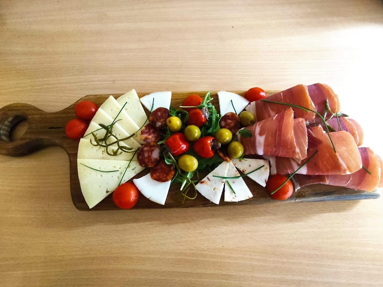 A board of cheese, cherry tomatoes and pršut
